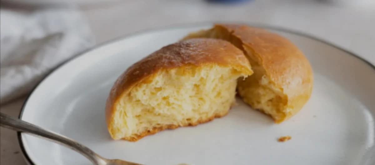 Brioche Bun Freshly baked soft bread roll split open on a white plate.