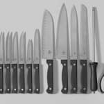 Full kitchen knife set including chef’s knives, steak knives, honing rod, and kitchen shears laid out on a flat surface.
