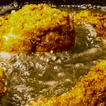 Fried Chicken cooking in hot oil inside a frying pan.