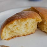 Brioche Bun Freshly baked soft bread roll split open on a white plate.