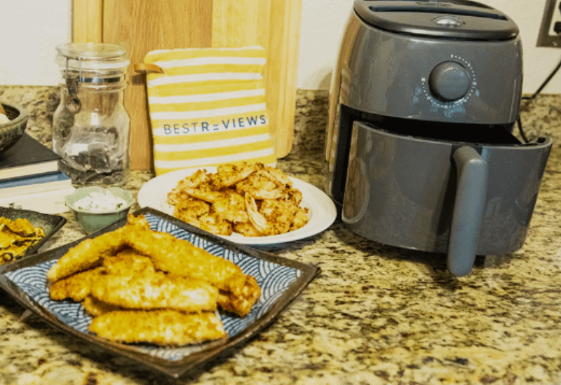 Air Fryers next to plates of fried fish and shrimp on a kitchen counter
