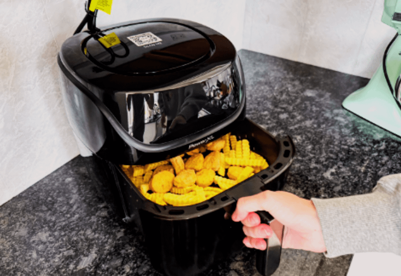 Air Fryers with freshly cooked fries and nuggets being pulled out by hand